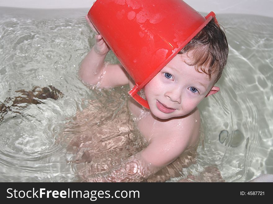 Boy in bath with pail