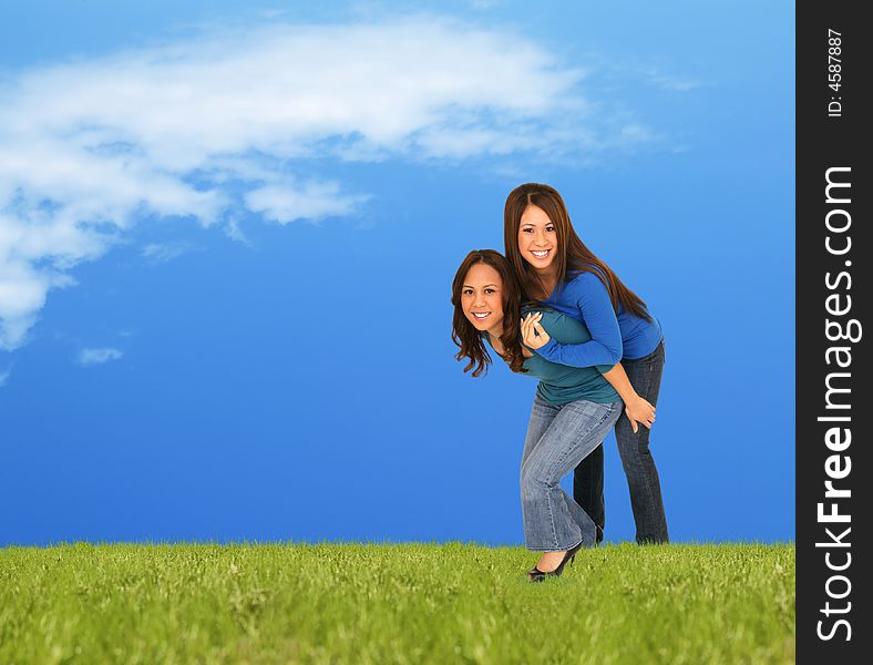 Two girls playing piggyback outside on the grass in beuatiful spring or summer shot. Two girls playing piggyback outside on the grass in beuatiful spring or summer shot