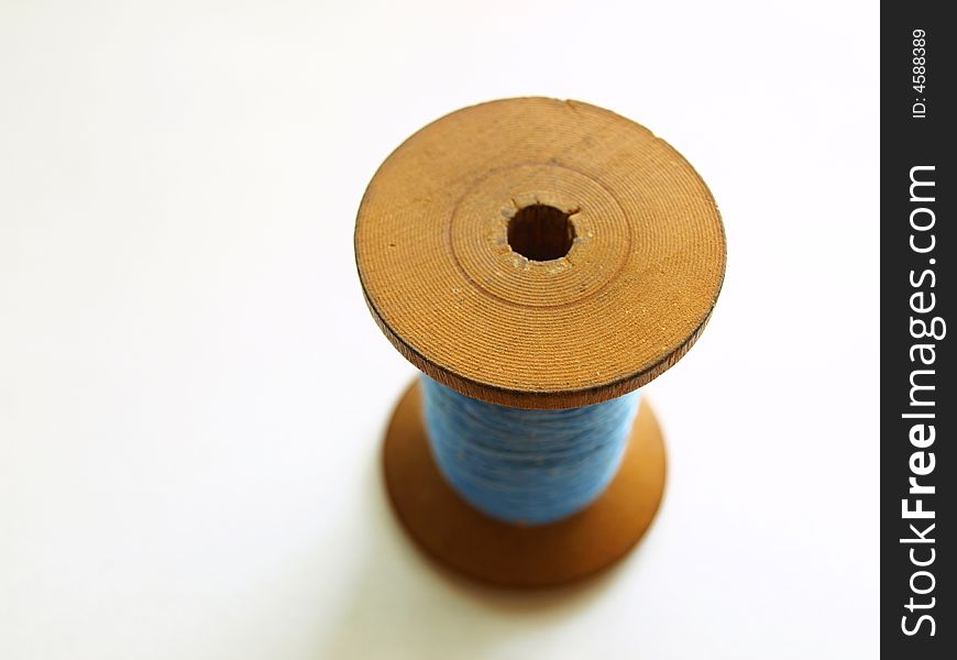 Photo of wooden bobbin with blue, cotton thread. Photo of wooden bobbin with blue, cotton thread