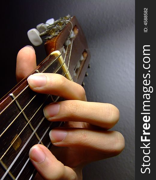 Fingers picking chord on acoustic guitar neck, playing the chord D/F#