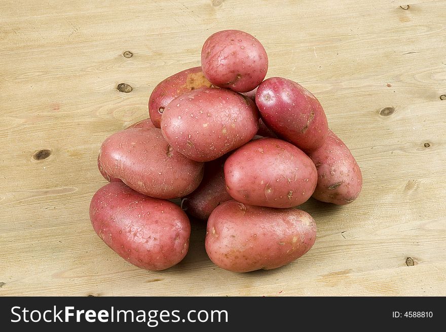 Red potatoes on a wooden kitchen table with a bright white background