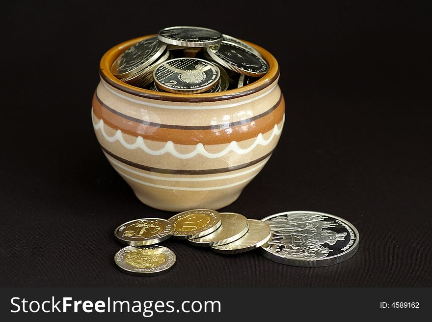 At the clay pot many silver coins lie, somewhat lies near the pot.