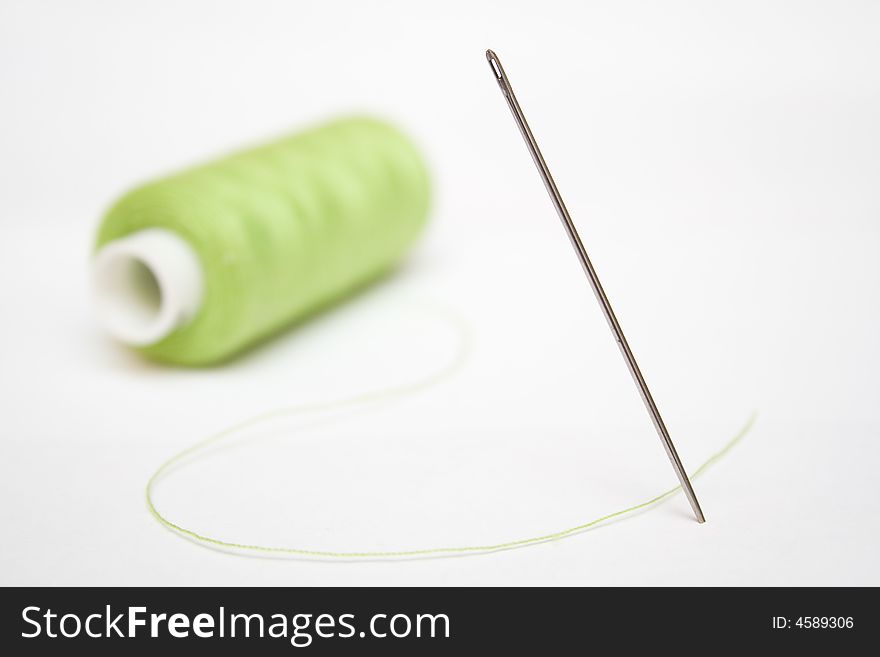 Green sewing and steel needle on a white isolated background