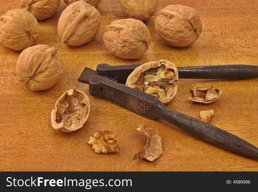 Walnuts with old iron nutcracker on wooden table. Walnuts with old iron nutcracker on wooden table