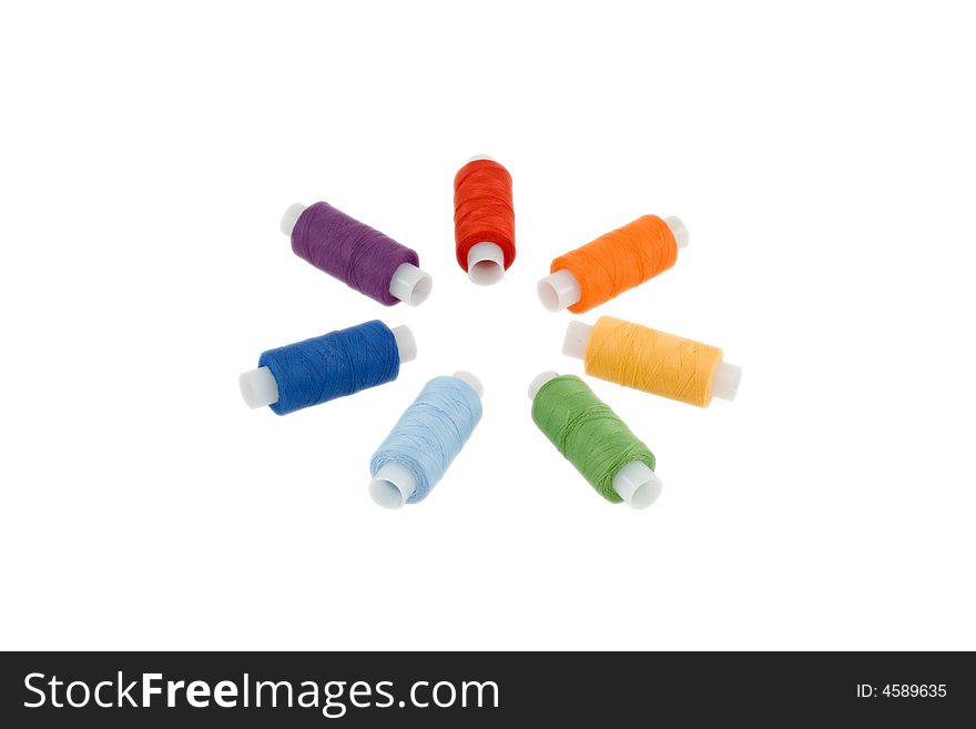 Seven sewing spools disposed as a circle in the spectrum order isolated over white. Seven sewing spools disposed as a circle in the spectrum order isolated over white