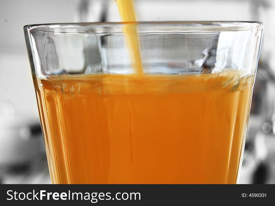 A closeup of a large glass of fresh orange juice as it is being filled. A closeup of a large glass of fresh orange juice as it is being filled.