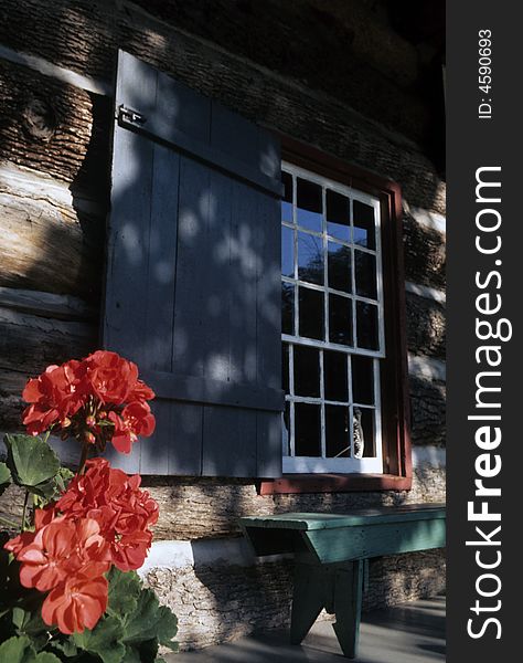 Flowers adorne the porch of a log cabin