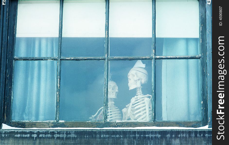 A couple of skeletons are looking out the window. A couple of skeletons are looking out the window