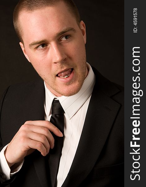 Portrait of a young businessman with tungpiercing on dark background