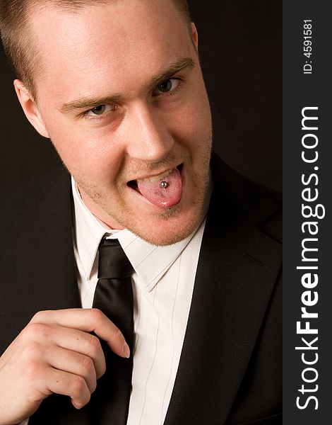 Portrait of a young businessman with tungpiercing on dark background