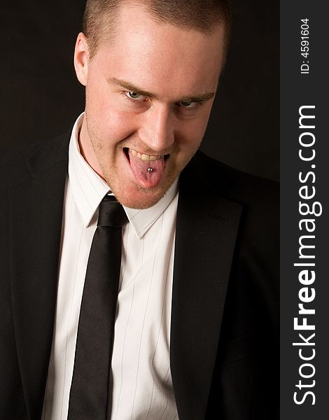 Portrait of a young businessman with tungpiercing on dark background