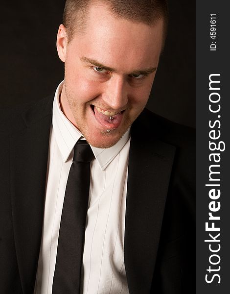 Portrait of a young businessman with tungpiercing on dark background