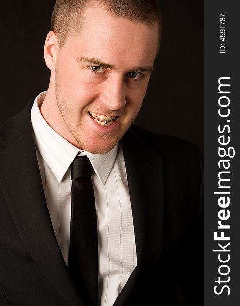 Portrait of a young businessman with tungpiercing on dark background