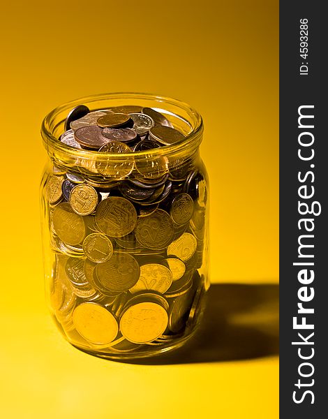 Business metaphor: glassy jar with Russian coins over yellow