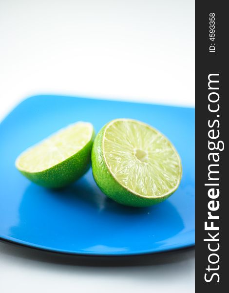 Macro shot of limes on blue plate with out of focus background. Macro shot of limes on blue plate with out of focus background.