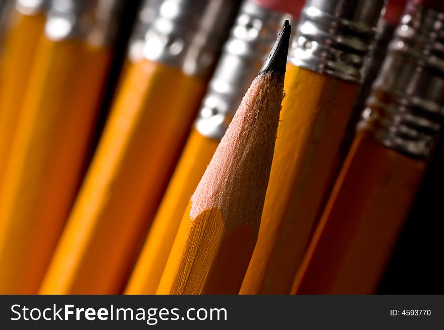 Macro of yellow pencils, focus is on the sharp pencil lead the rest of the pencils are out of focus, copy space to the left. Macro of yellow pencils, focus is on the sharp pencil lead the rest of the pencils are out of focus, copy space to the left