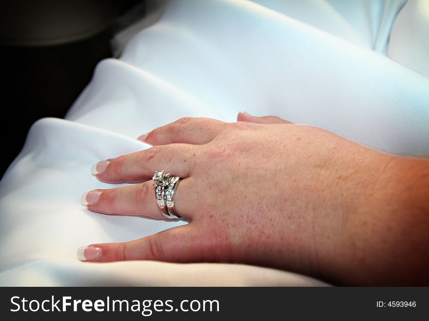 Bride's hand on her dress showing her wedding ring