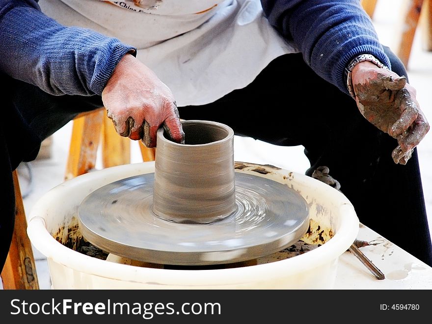 A craftsman is making a pot on a revovling potter's wheel,Foshan,Guangdong,China. A craftsman is making a pot on a revovling potter's wheel,Foshan,Guangdong,China.