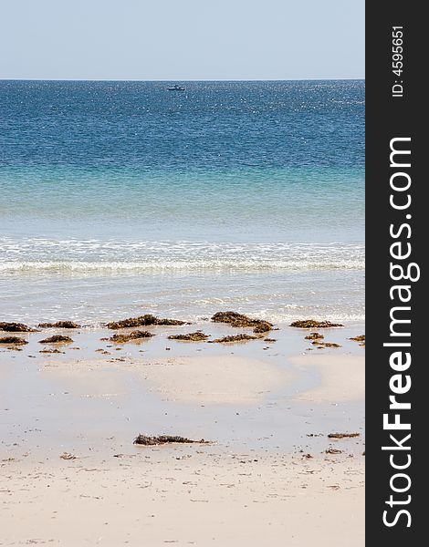 A beach and a lone boat on the ocean. A beach and a lone boat on the ocean