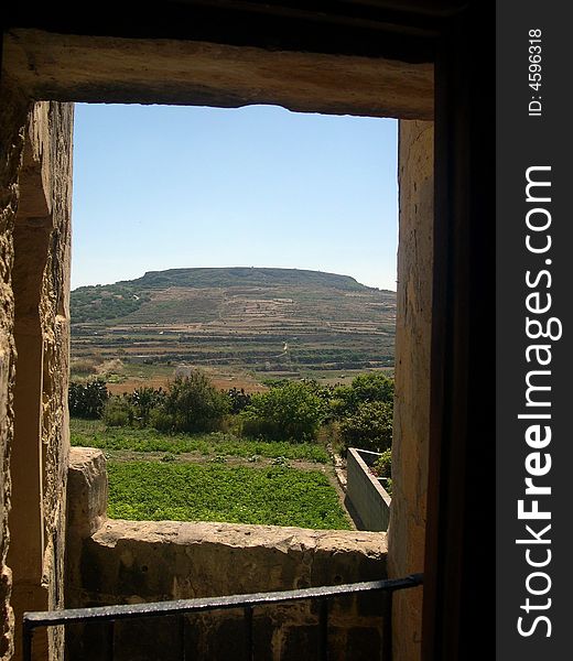 An old farmhouse window looks out over a farmer's field in the village of Gharb in Gozo, Malta. An old farmhouse window looks out over a farmer's field in the village of Gharb in Gozo, Malta