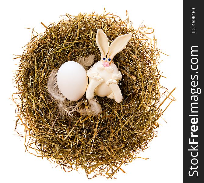 Easter white toy rabbit and white egg a nest from a dry grass on a white background. Easter white toy rabbit and white egg a nest from a dry grass on a white background