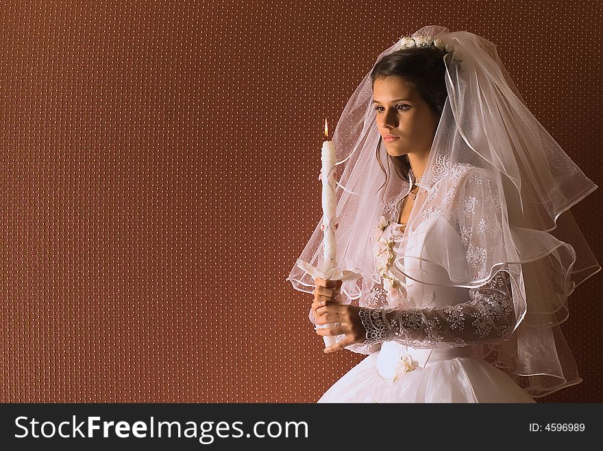 The wedding bride with a candle on brown background
