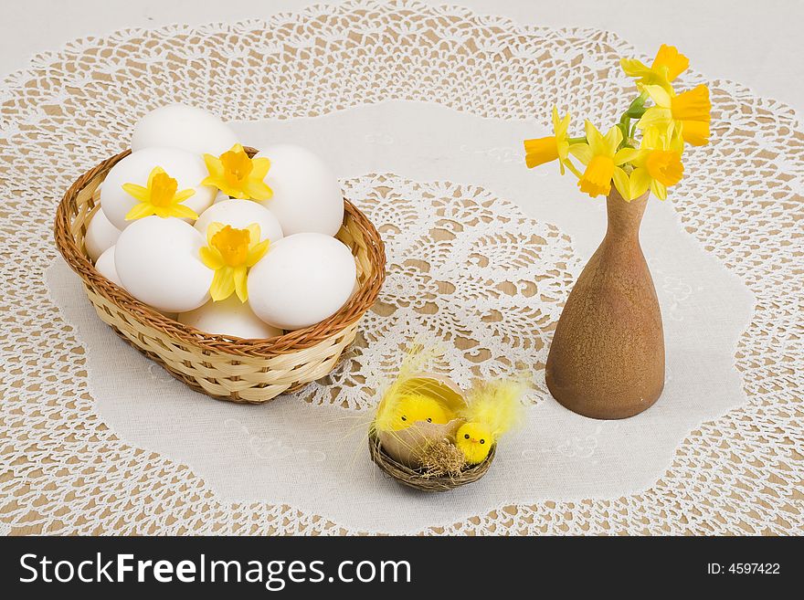 A basket of eggs, easter chicken and yellow daffodils