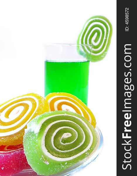 Multi-coloured fruit candy and cold green drink on a white background. Multi-coloured fruit candy and cold green drink on a white background