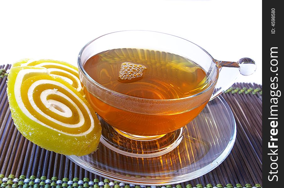 Multi-coloured fruit candy and cup of tea on a white background. Multi-coloured fruit candy and cup of tea on a white background