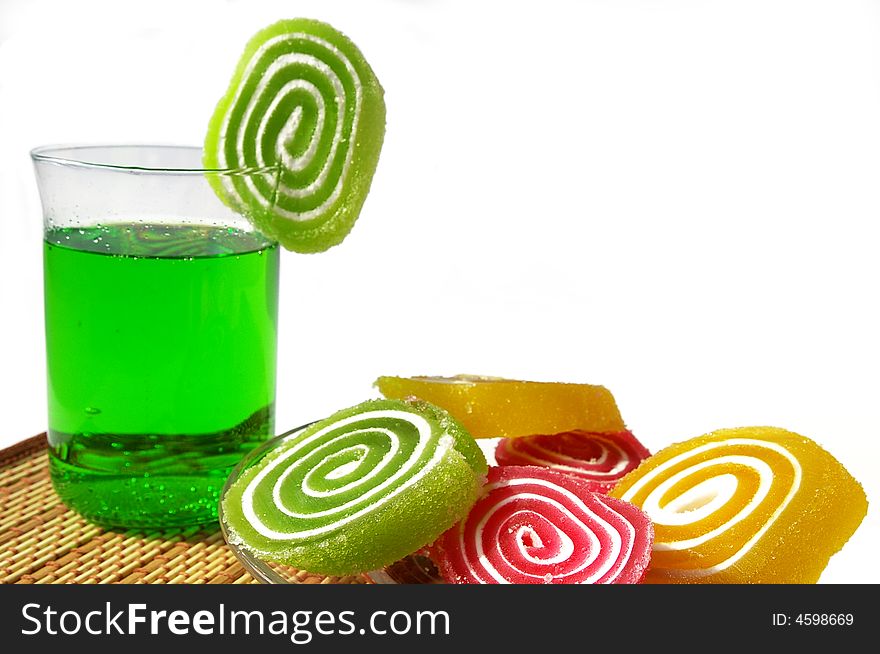 Multi-coloured fruit candy and cold green drink on a white background