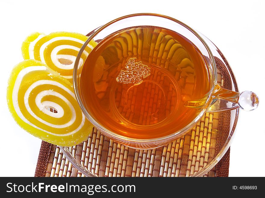 Multi-coloured fruit candy and cup of tea on a white background. Multi-coloured fruit candy and cup of tea on a white background