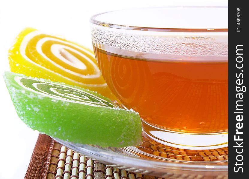 Multi-coloured fruit candy and cup of tea on a white background