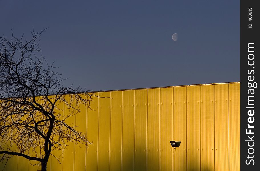 Sun reflection on warehouse wall and moon still in sky, -28C cold weather. Sun reflection on warehouse wall and moon still in sky, -28C cold weather