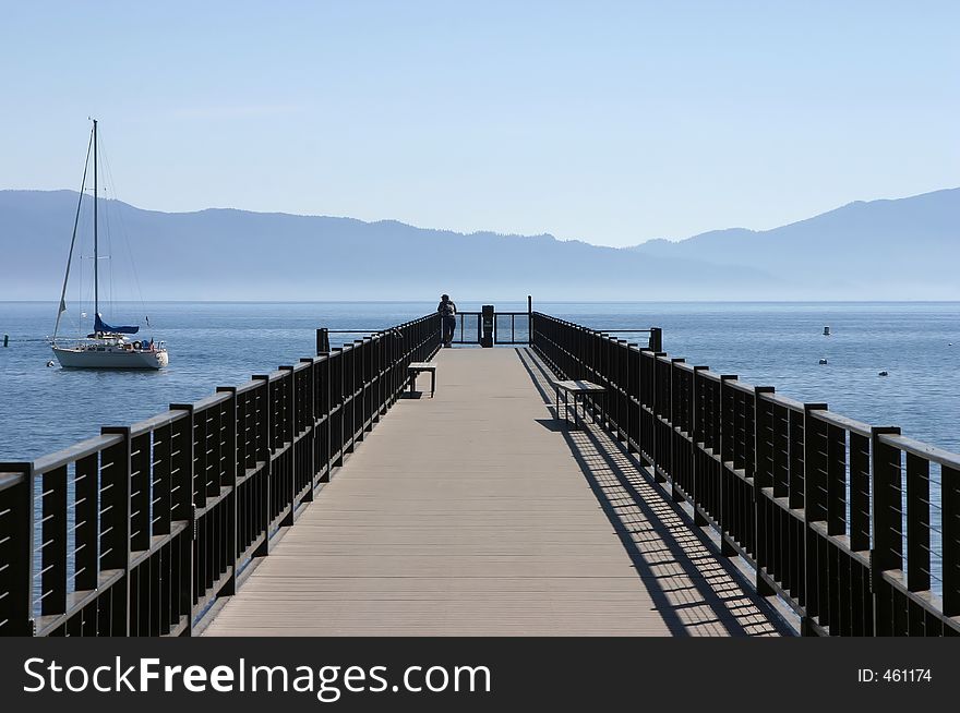 A pier extends into a beautiful mountain lake. A pier extends into a beautiful mountain lake.