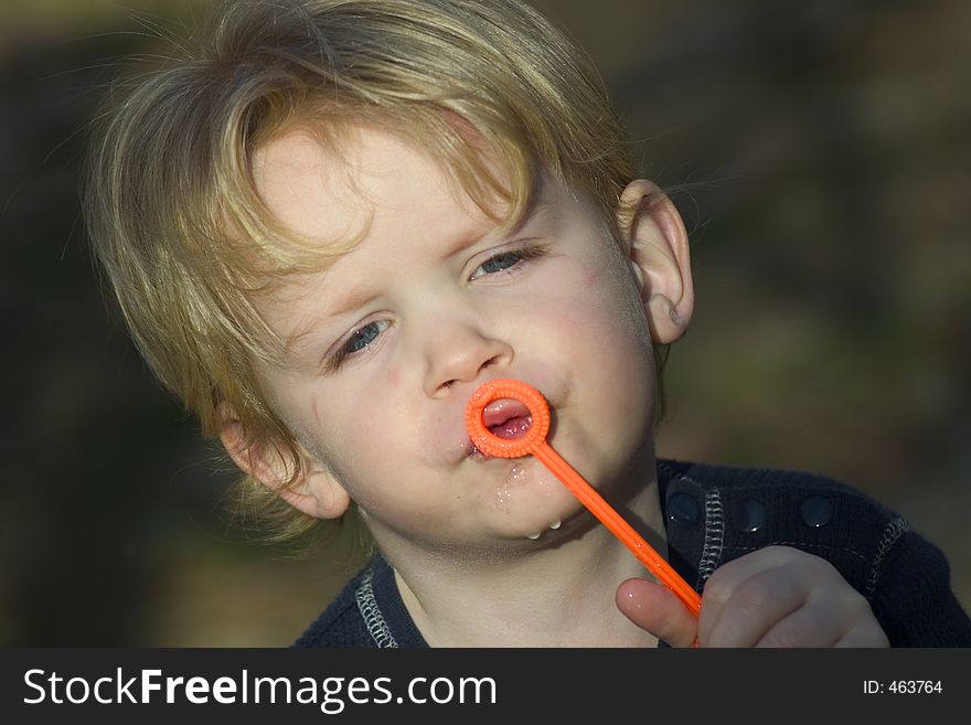2 year old boy trying to blow bubbles at park. Model released. 2 year old boy trying to blow bubbles at park. Model released