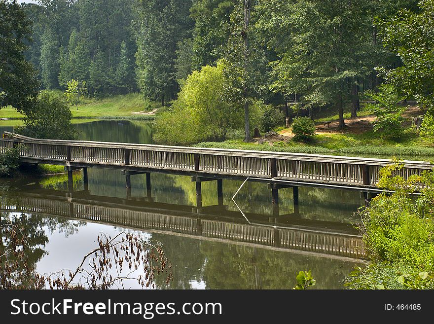 A wooden bridge over a peaceful pond