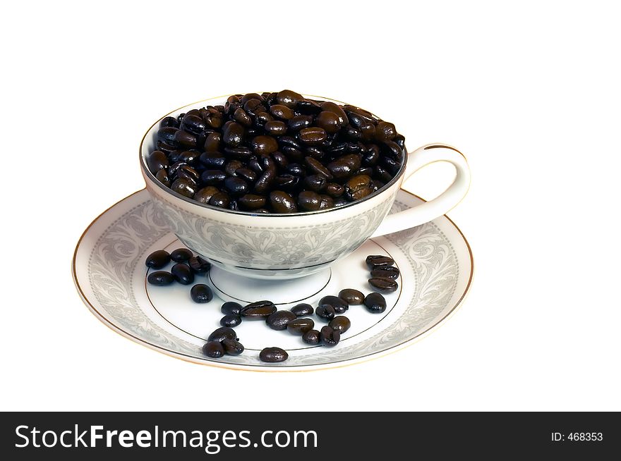 China cup on saucer filled with coffee beans on white background. China cup on saucer filled with coffee beans on white background