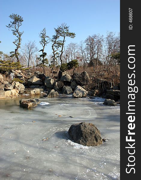 Pond frozen over with waterfall in the background. Pond frozen over with waterfall in the background