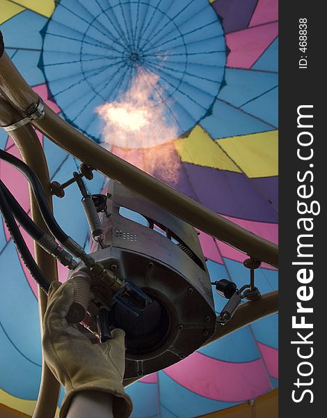 Balloon pilot's gloved hand firing the jet in a colorful hot air balloon. Balloon pilot's gloved hand firing the jet in a colorful hot air balloon