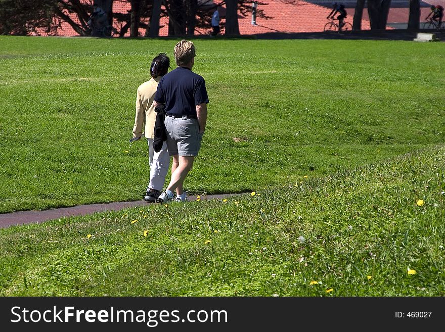 A middle-aged couple strolls along a path in the midst of a grass field. A middle-aged couple strolls along a path in the midst of a grass field.
