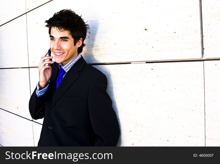 Smiling businessman at phone over white wall