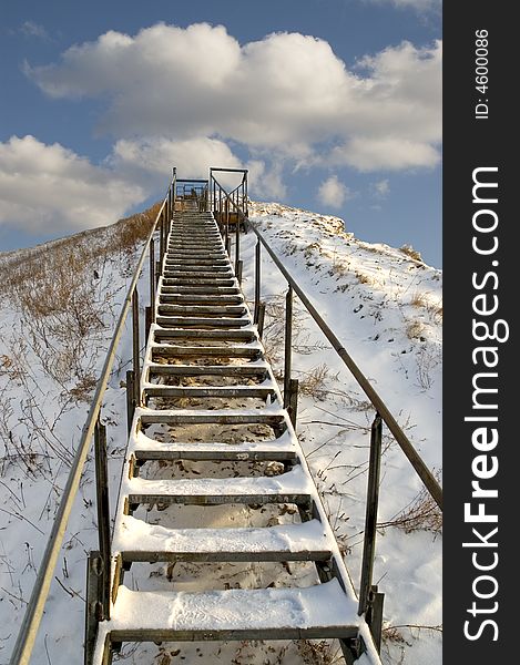 Ladder on a snow mountain on a background of the light-blue sky. Ladder on a snow mountain on a background of the light-blue sky.