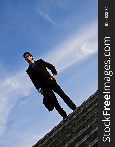 Businessman posing on stairs against blue sky. Businessman posing on stairs against blue sky.