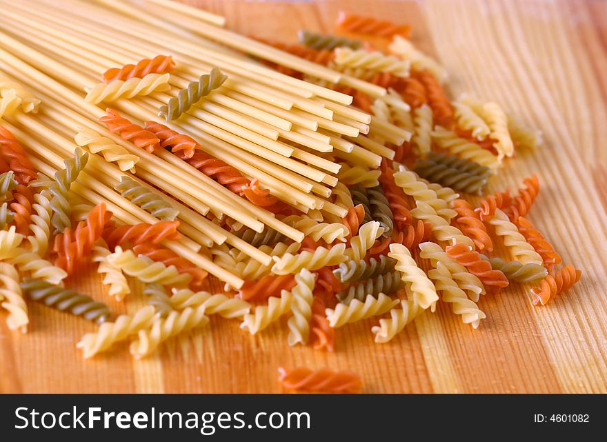 Raw colour pasta background on yellow wooden cook-table. Raw colour pasta background on yellow wooden cook-table