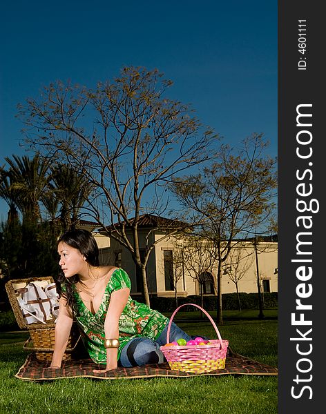 Asian female sitting on her picnic blanket surrounded by blankets looking to camera left. Asian female sitting on her picnic blanket surrounded by blankets looking to camera left.