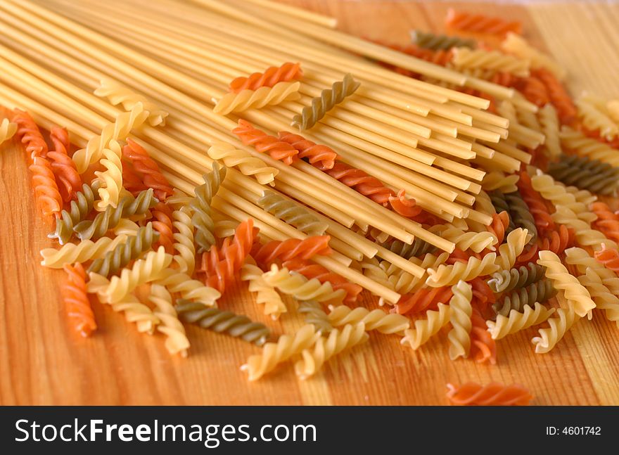 Raw colour pasta background on yellow wooden cook-table. Raw colour pasta background on yellow wooden cook-table