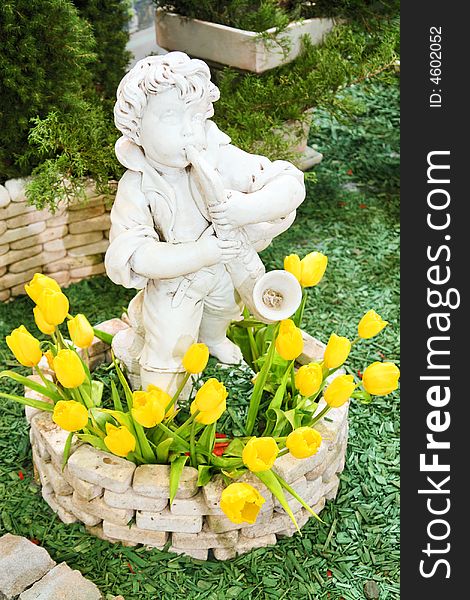 Statue of a boy with saxaphone in flowerbed with tulips in the park. Statue of a boy with saxaphone in flowerbed with tulips in the park