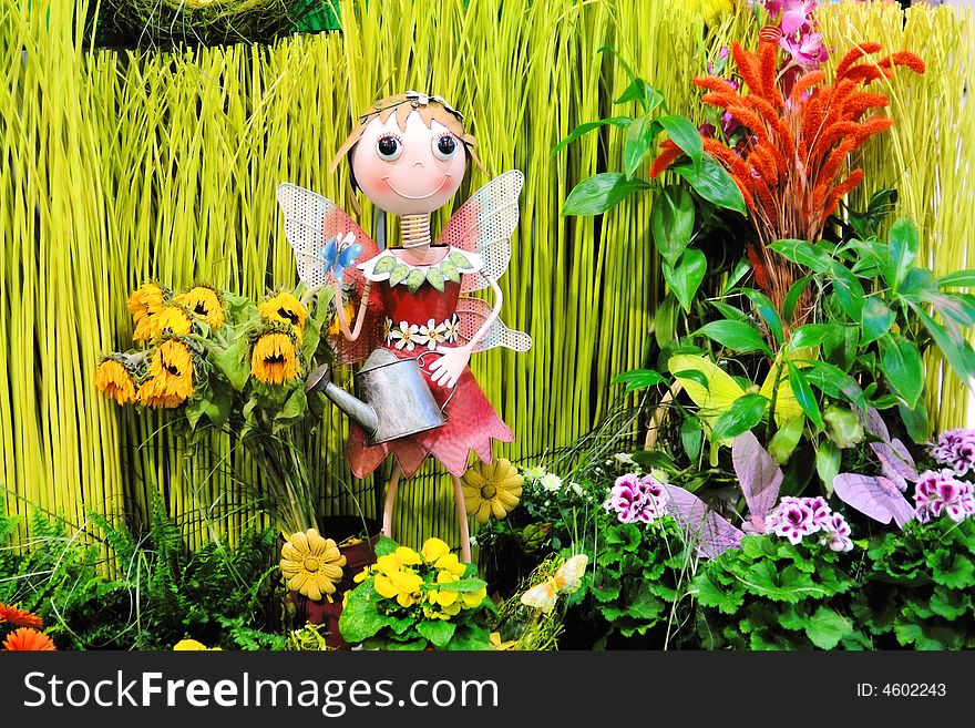 Figure of a girl watering flowers in a garden. Figure of a girl watering flowers in a garden