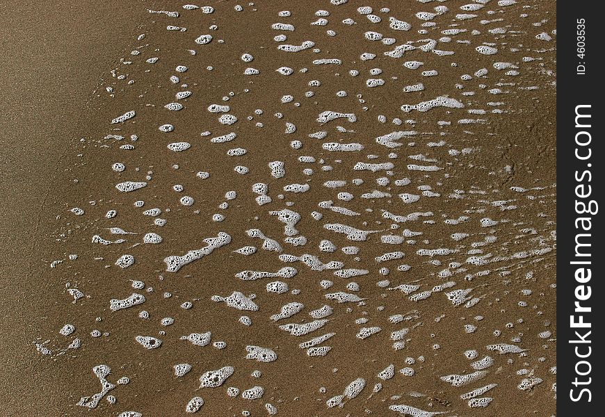 Bubbles on sand caused by receeding tide on a beach
