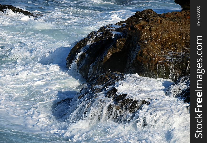 Closeup of wave breaking on rocks creating sea foam. Closeup of wave breaking on rocks creating sea foam
